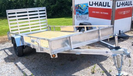 Silver utility trailer with wooden bed, near a U-Haul truck.