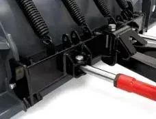 Close-up view of a black snowplow blade attachment with a red handle and metal springs.