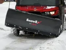 Red UTV with black SnowEx plow clearing snow.