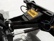 Close-up of a snow plow attachment. Black metal, silver cylinder, yellow 