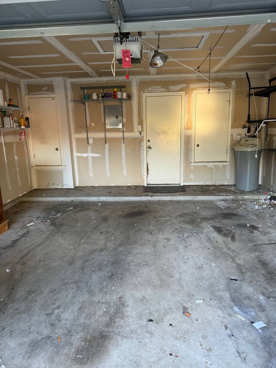 An empty garage with a door and a trash can