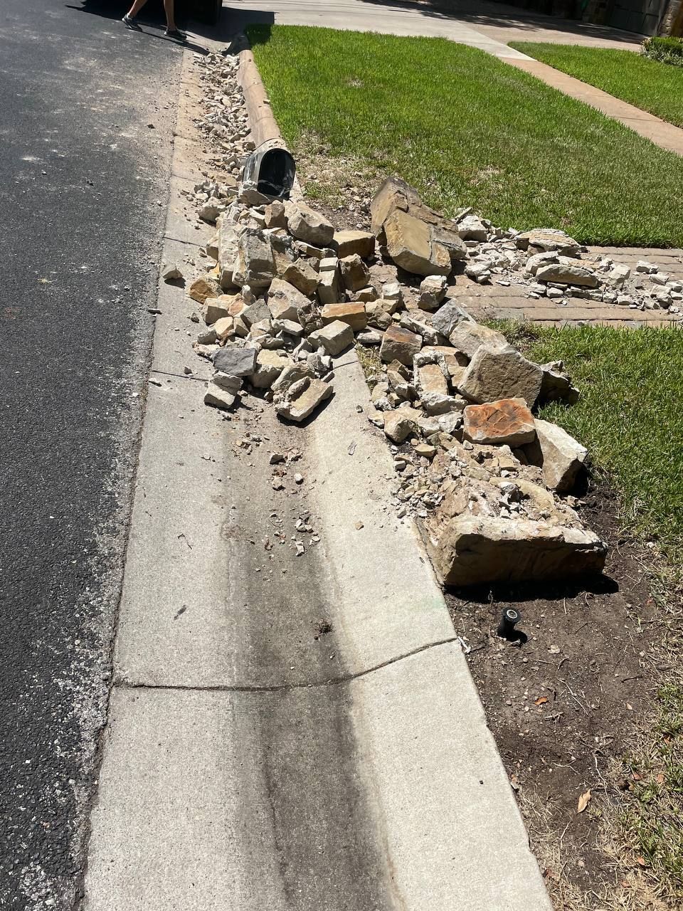 A pile of rocks on the side of a road next to a curb.