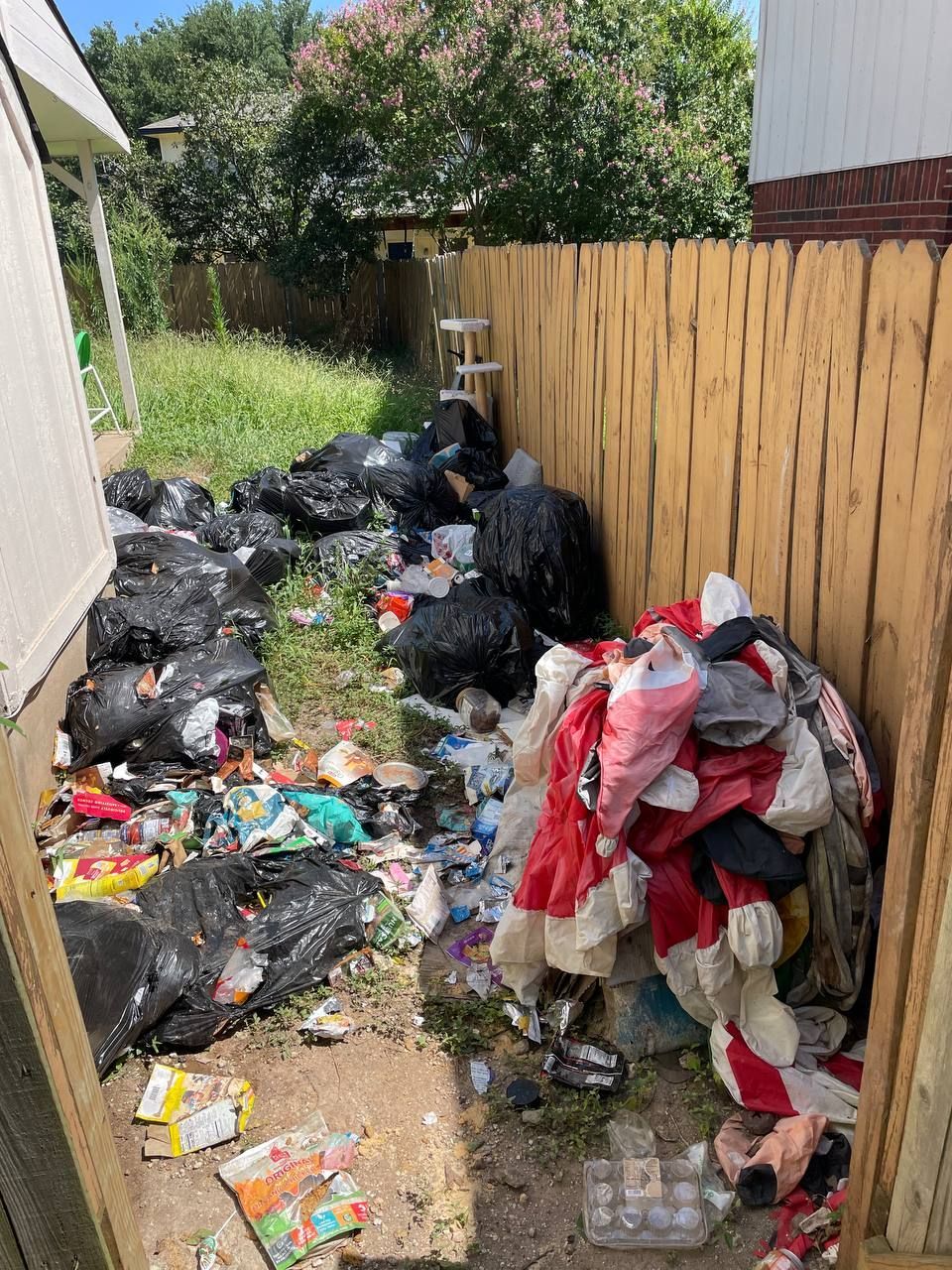 There is a lot of trash in the backyard of a house.