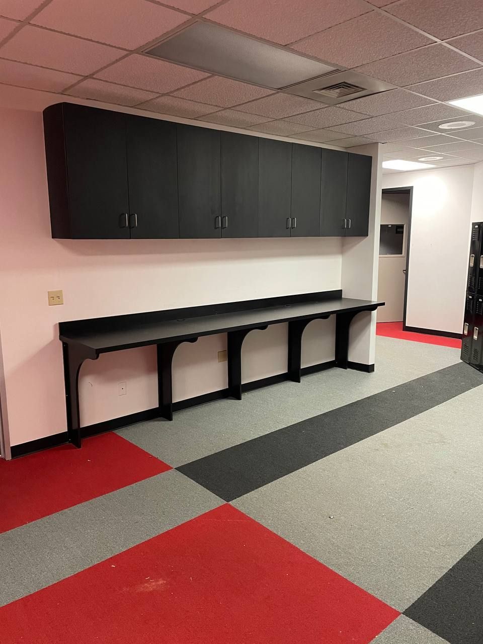 A room with a carpeted floor and a row of tables