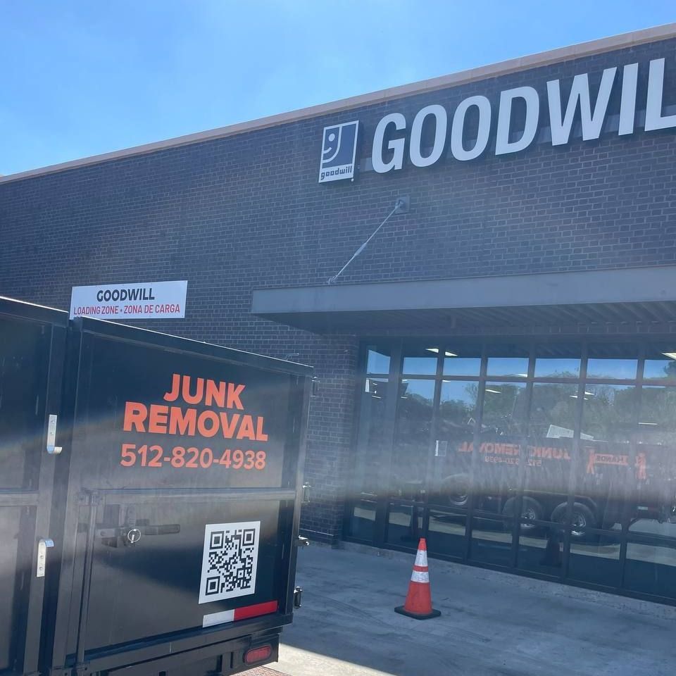 A junk removal truck is parked in front of a goodwill store.