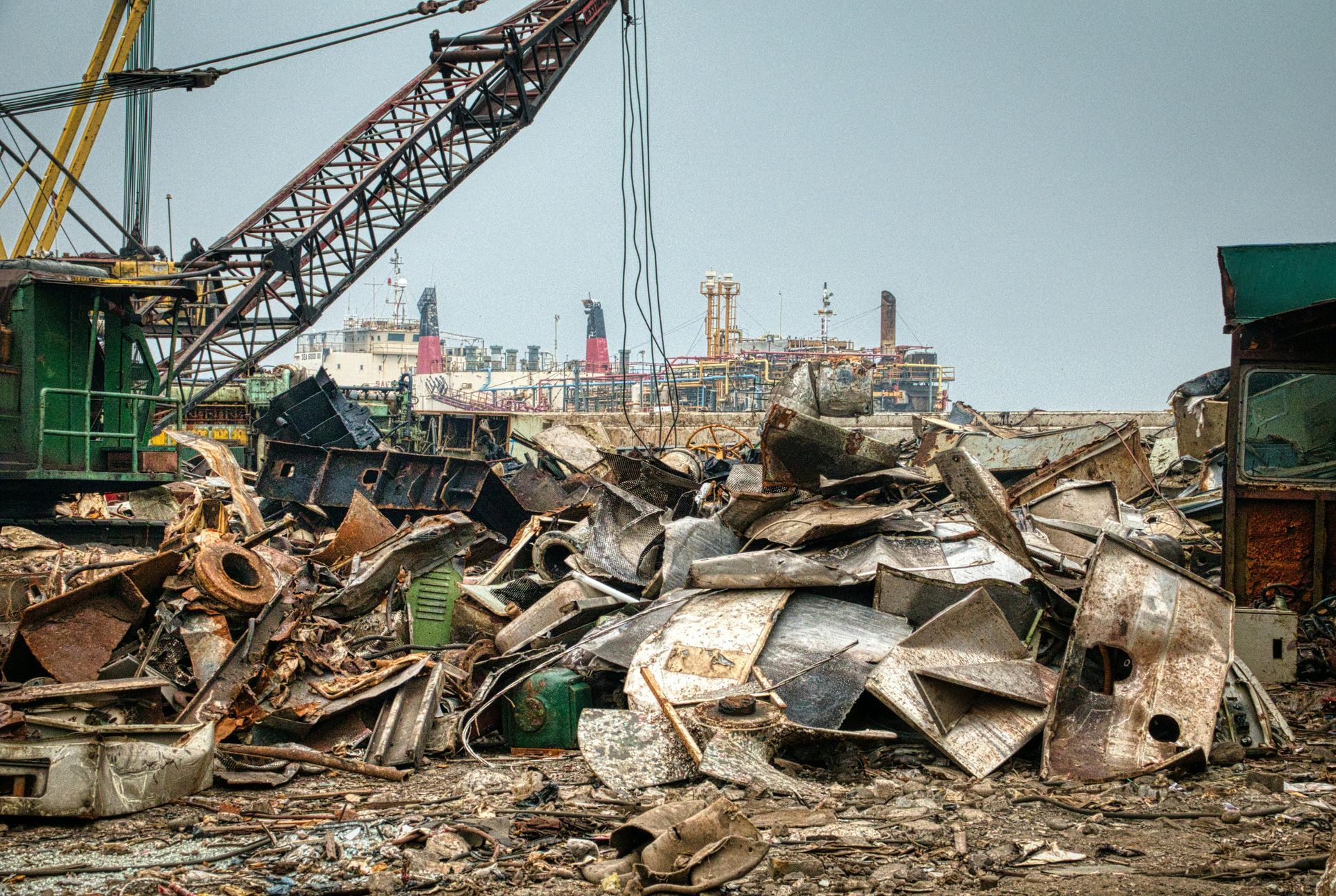 A pile of scrap metal with a crane in the background.