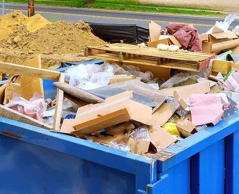 A blue dumpster filled with lots of cardboard and plastic.