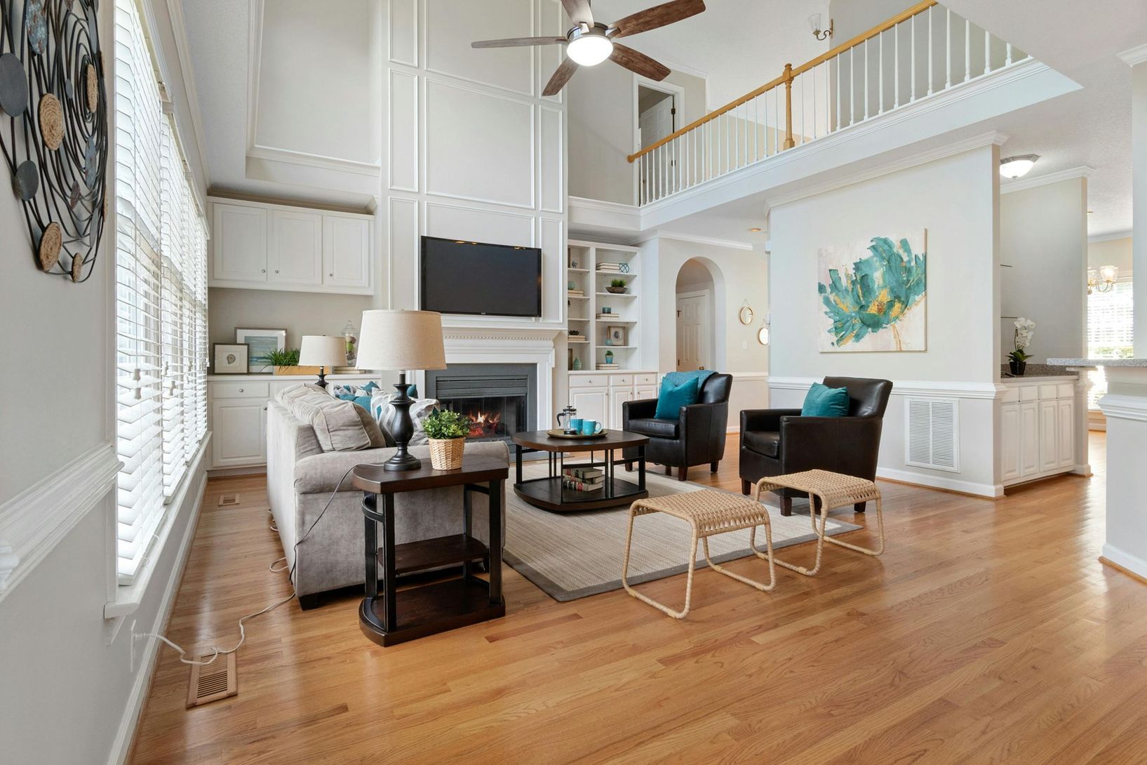 Bright open living room with vaulted ceiling, fireplace, gray sofa, blue chairs, and hardwood floors
