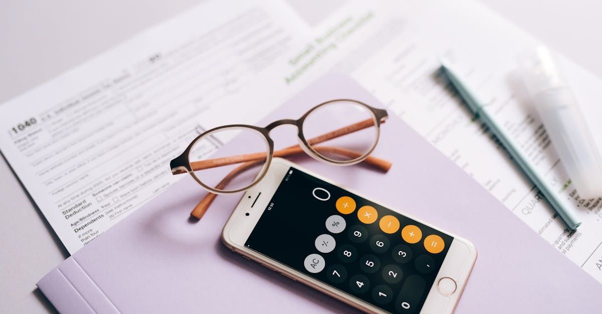 A pair of glasses is sitting on top of a cell phone next to a calculator.