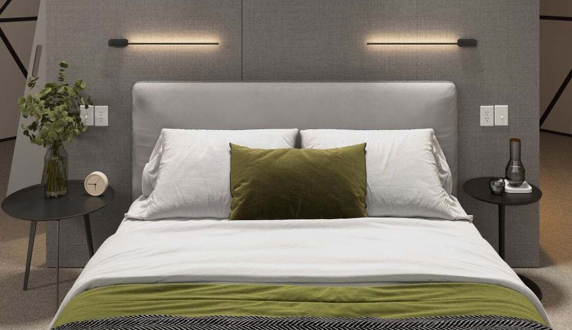 Modern bedroom with gray headboard, white bedding, and green accent pillows and throw blanket