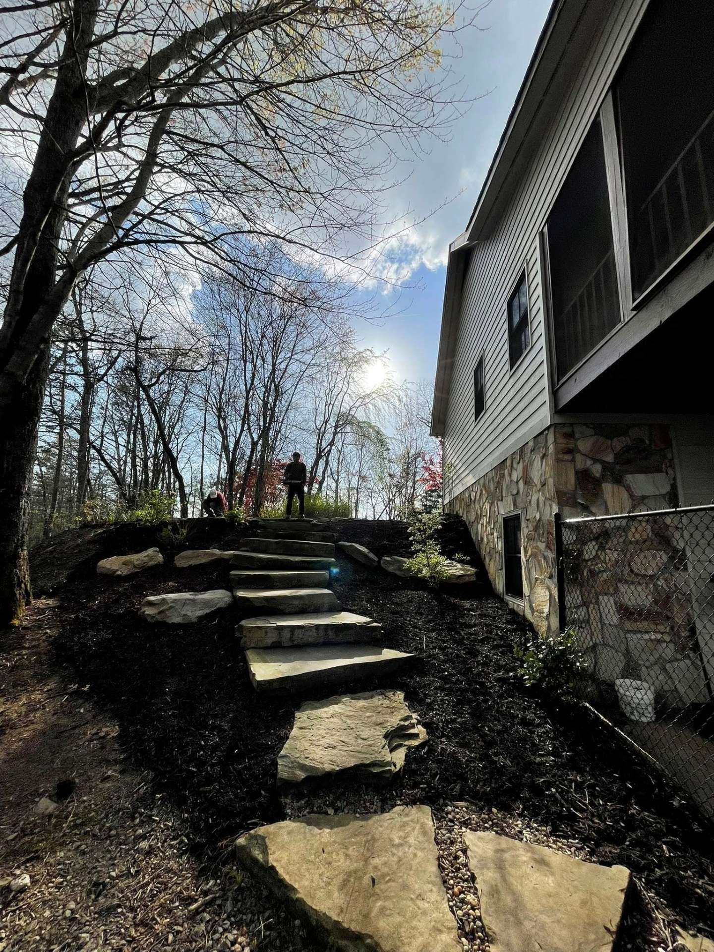 Woman in straw hat smiles, holding wine glass near a lake.