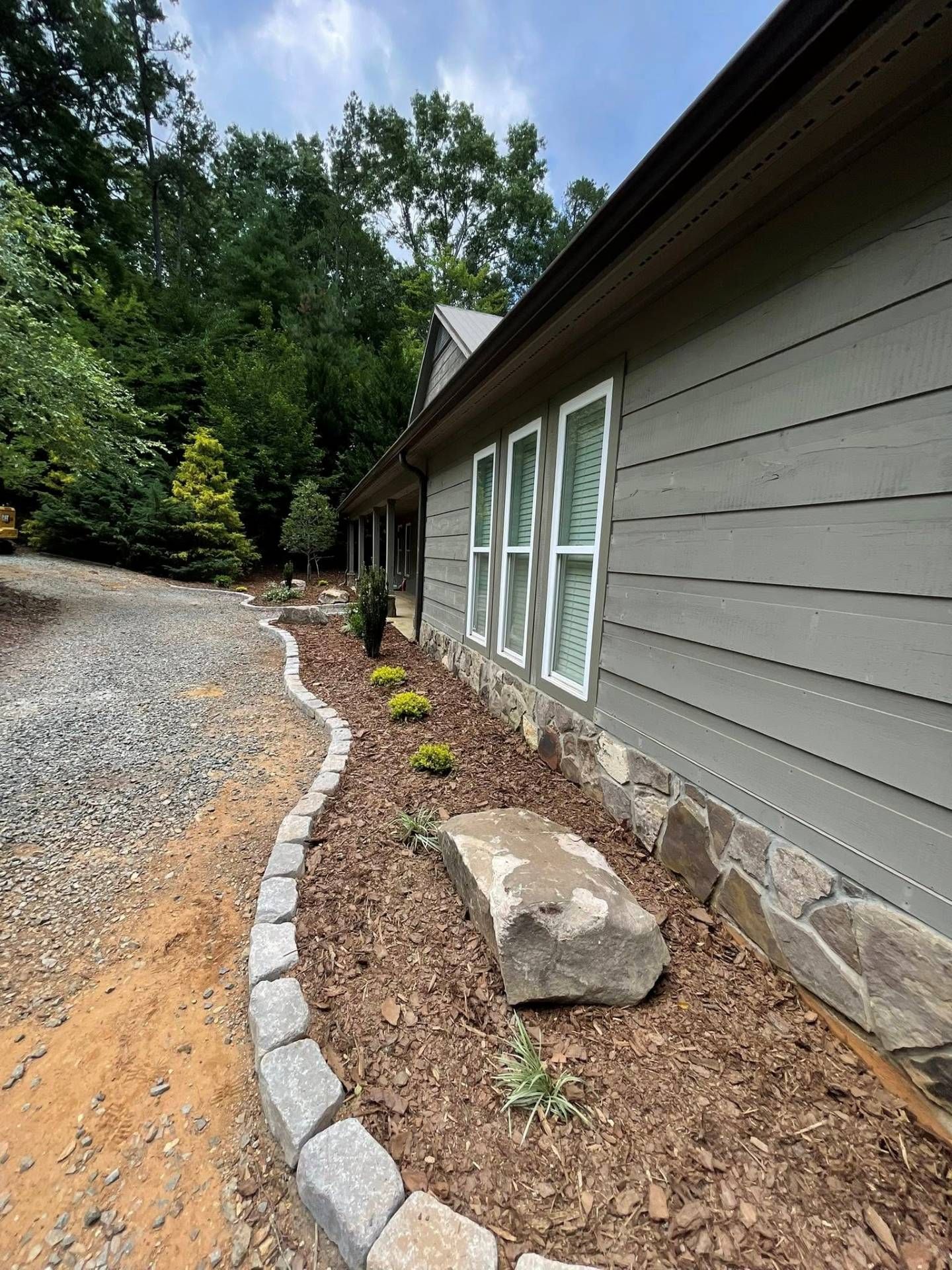 Woman in straw hat smiles, holding wine glass near a lake.