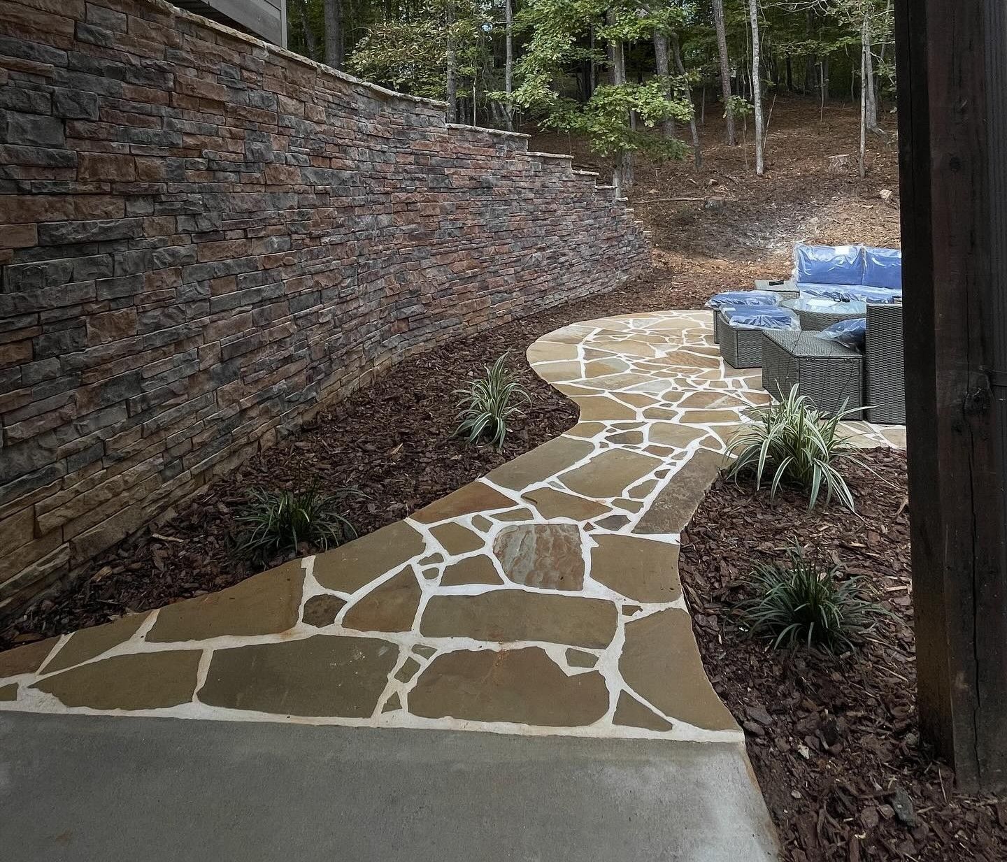 Woman in straw hat smiles, holding wine glass near a lake.