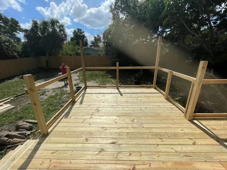 A wooden deck with railing under construction in a yard.