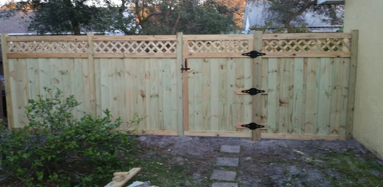 Wooden fence with gate, light green color. Black hinges and latch, lattice top.