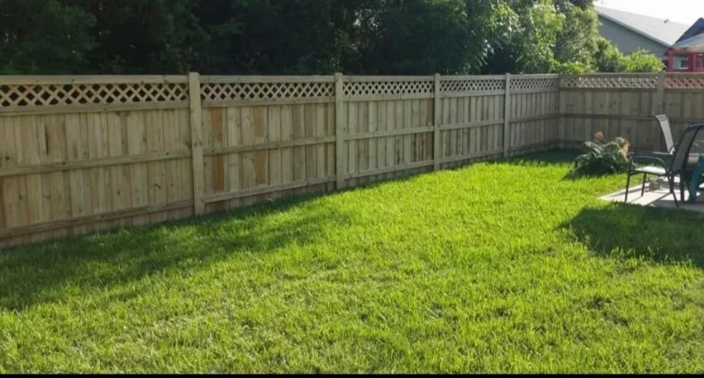Wooden fence encloses a green lawn, with a small seating area visible.