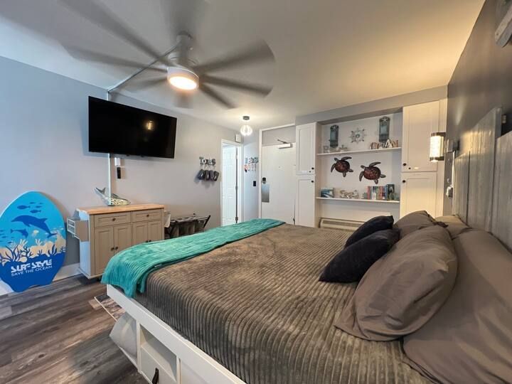 A bedroom with a king size bed , television and a ceiling fan.