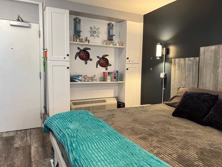A bedroom with a bed and a shelf with sea turtles on it