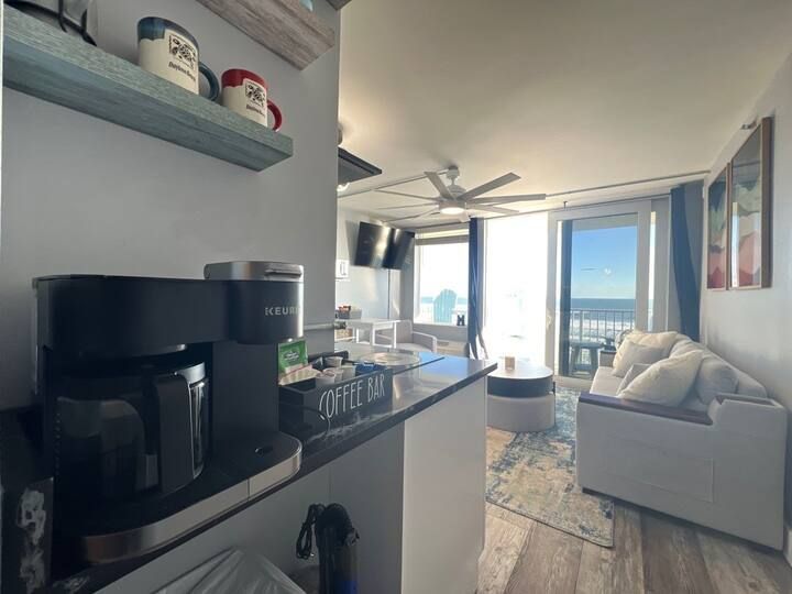 A living room with a coffee maker and a coffee bar.