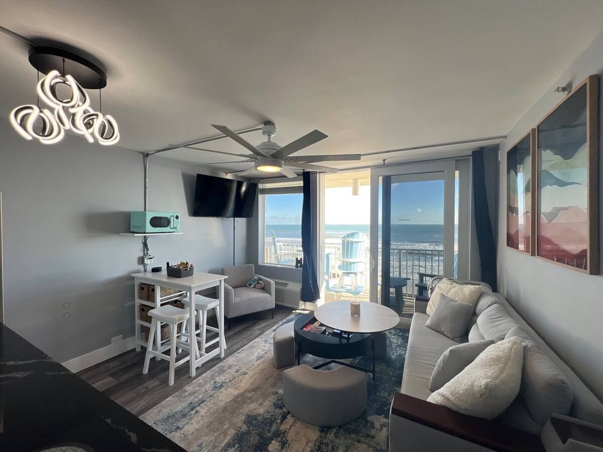 A living room with a couch , table , chairs and a ceiling fan.
