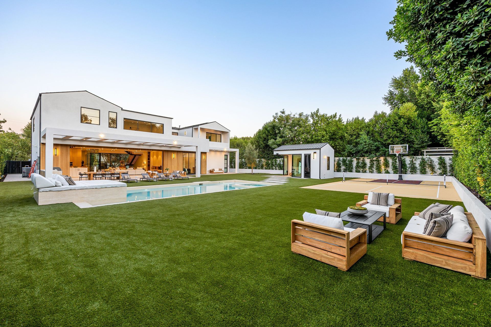 Large backyard with pool, lawn, outdoor seating, and modern house.