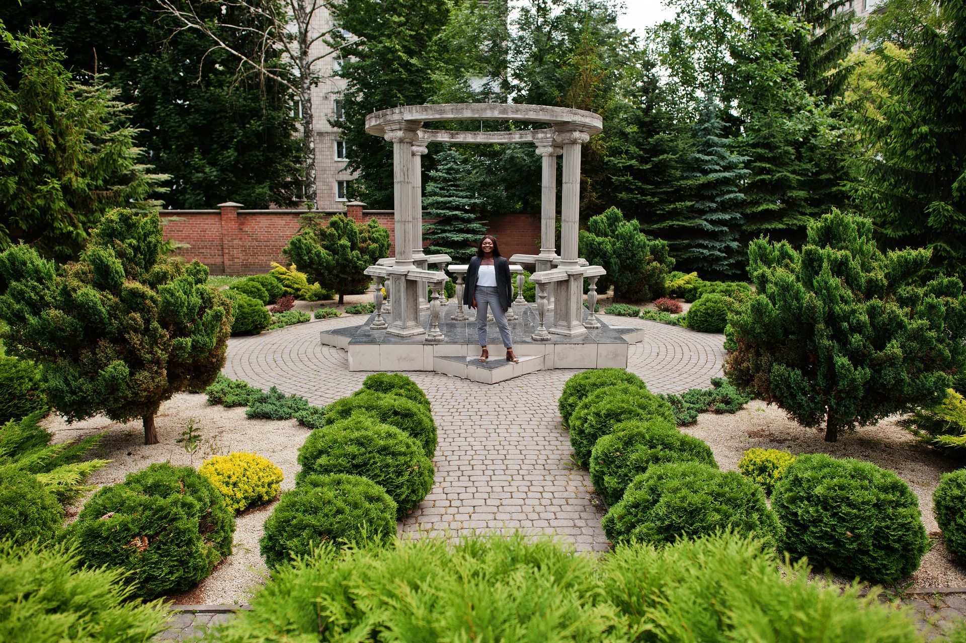A man standing in a garden with a gazebo in the background