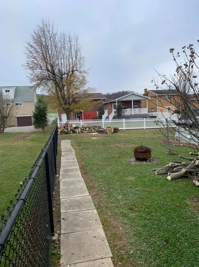 A walkway leading to a backyard with a chain link fence and a fire pit.