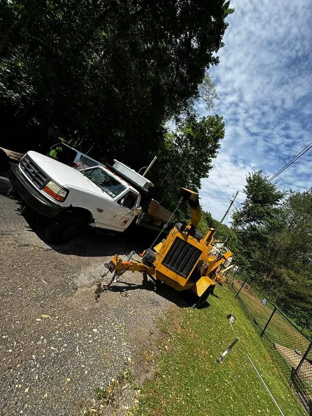 A white truck is parked on the side of the road next to a yellow machine.
