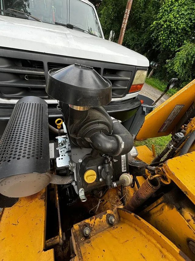 A white truck is parked next to a yellow truck with its hood open.