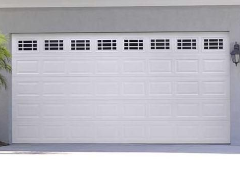 Modern white garage door with vertical window panels and black hardware in a Jacksonville residential neighborhood.