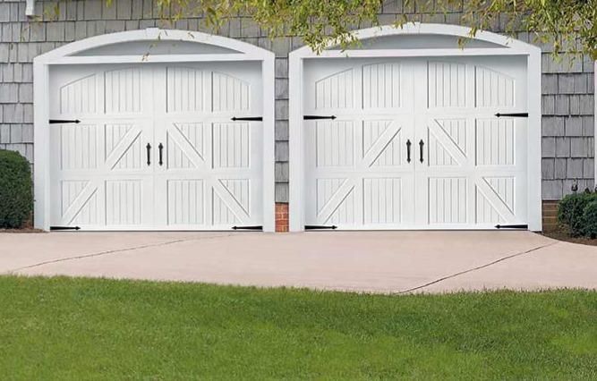 A garage with a black door is surrounded by trees.