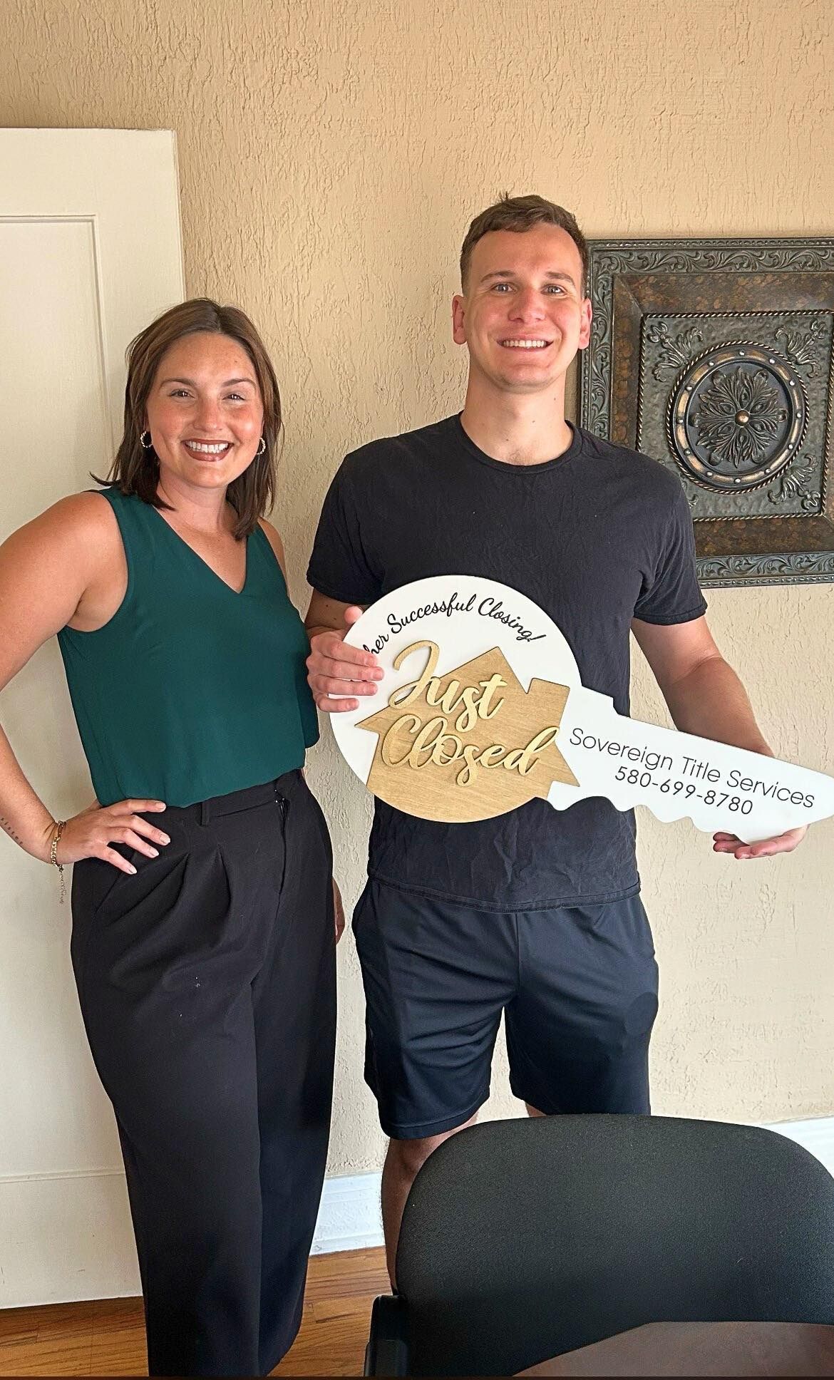 Woman and man holding a large key-shaped sign that reads