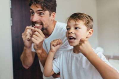 Dental Crowns — Father And Son Cleaning Their Teeth in Lexington, NE