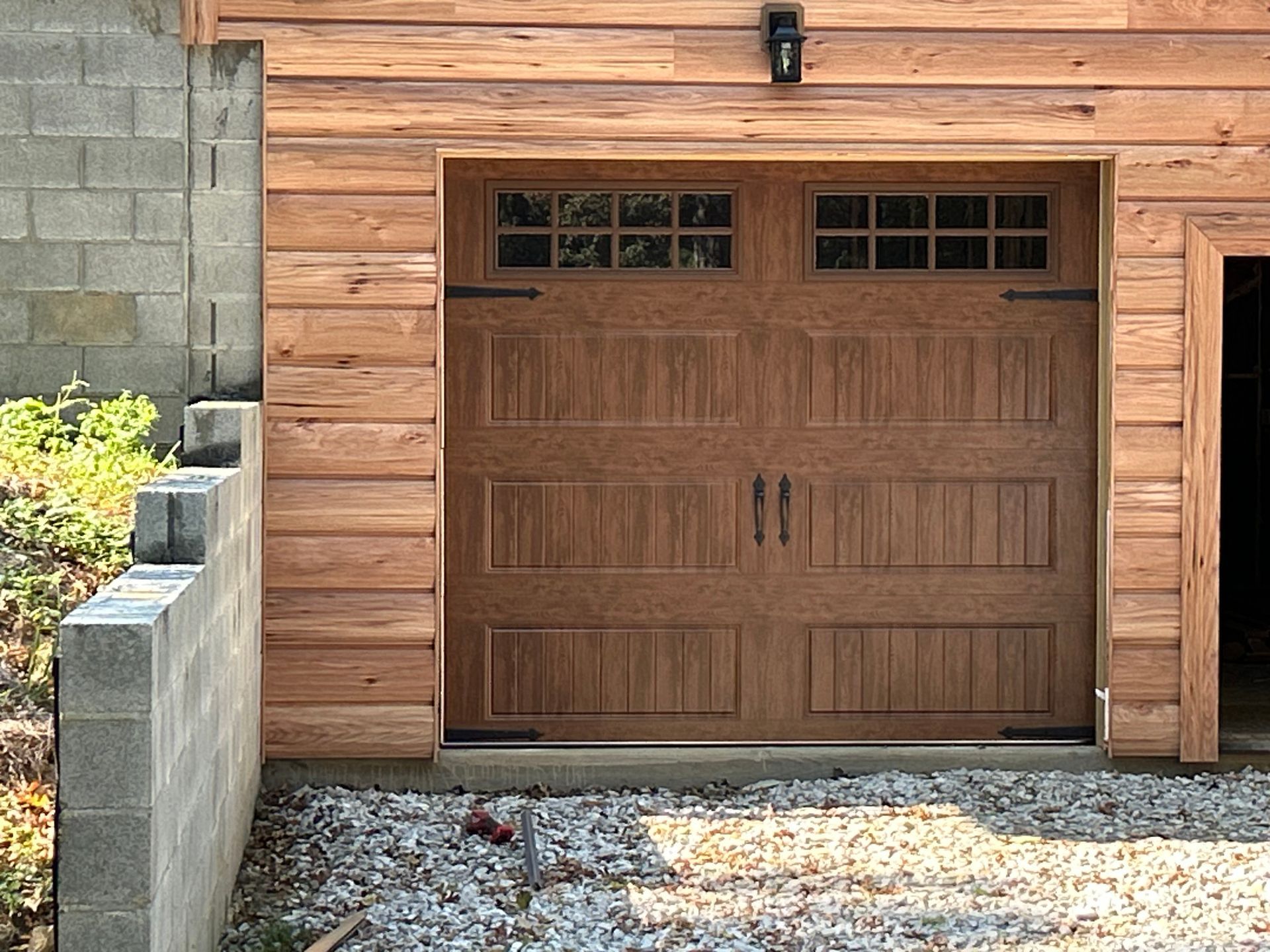 Wooden garage door with windowed top panels, set in wood siding. Wooden garage door with windowed top panels, set in wood siding.