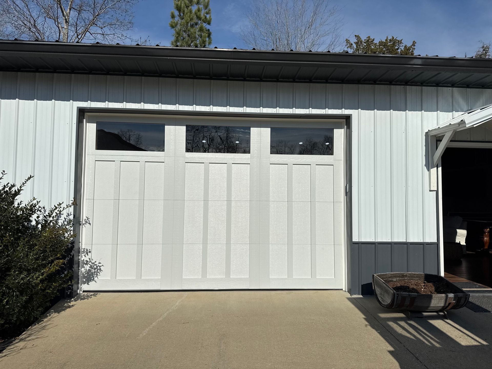 White garage door with glass panels on a building with white and gray siding. White garage door with glass panels on a building with white and gray siding.