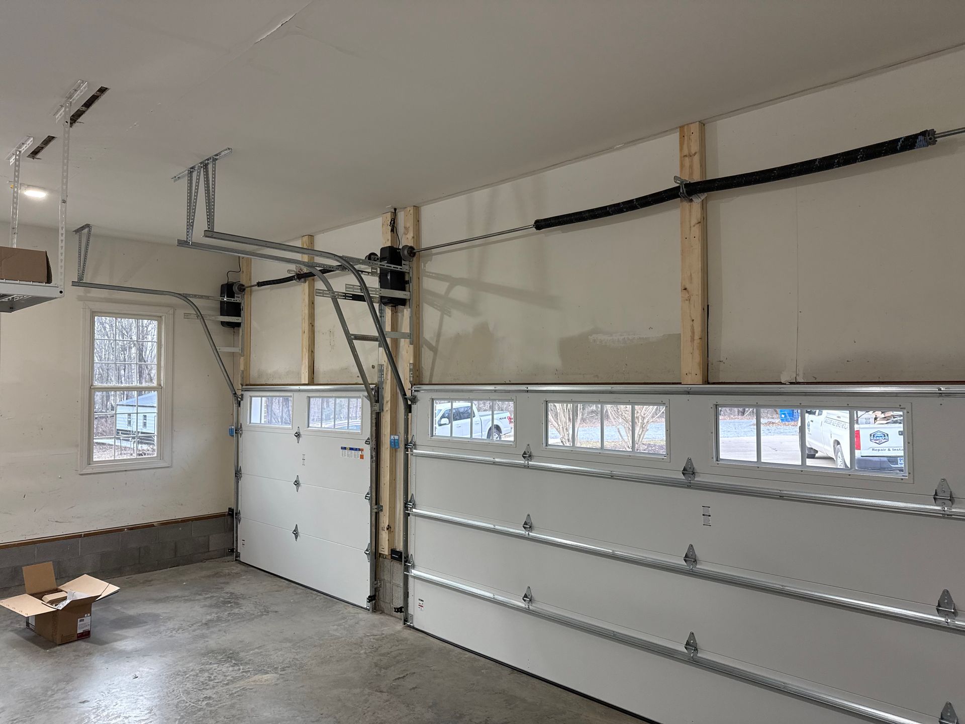 Garage interior with two white garage doors and an automated opening system. Garage interior with two white garage doors and an automated opening system.
