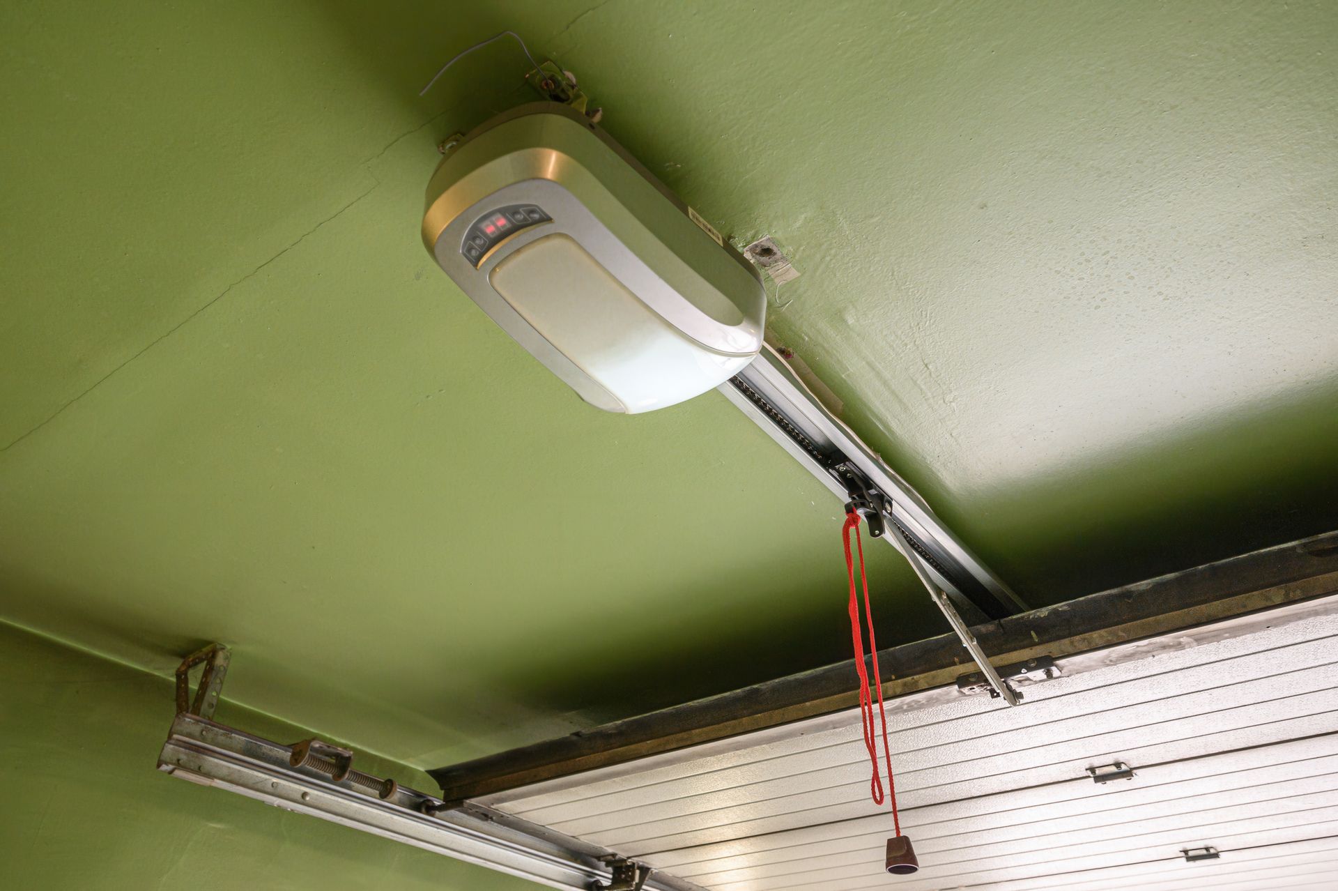 Garage door opener mounted on green ceiling.