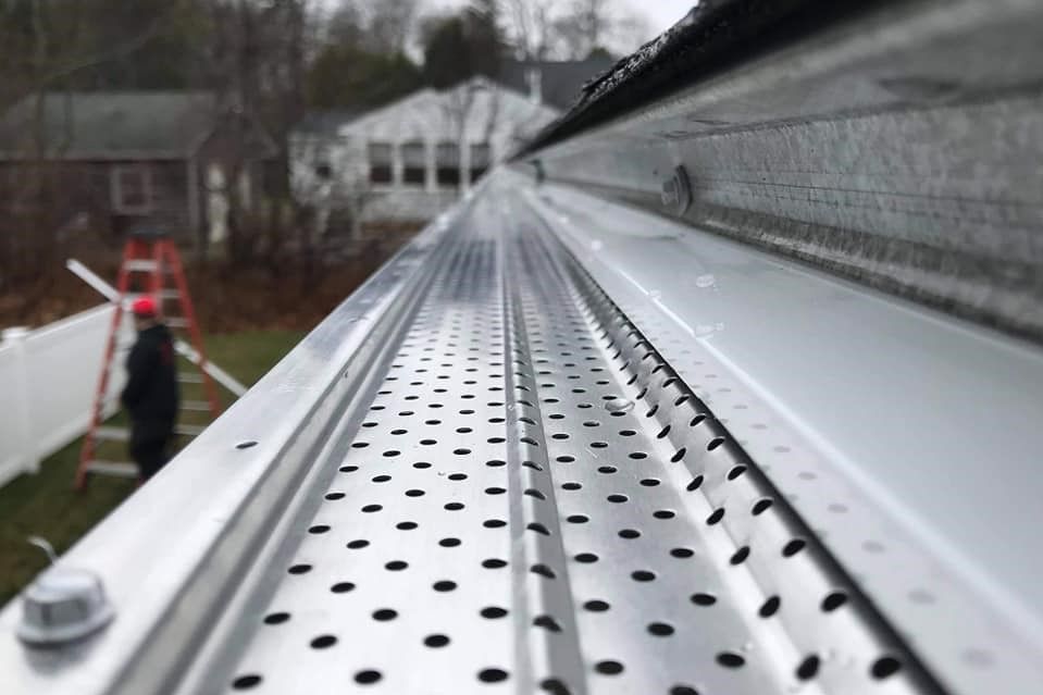 Metal gutter with perforated guard, installed on a house, exterior shot.