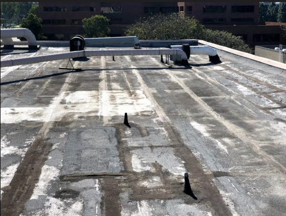 Flat, weathered roof with HVAC pipes and black rubber vent boots.