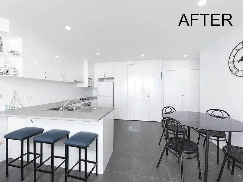 Modern white kitchen with island, stools, table and chairs, gray floors, and 