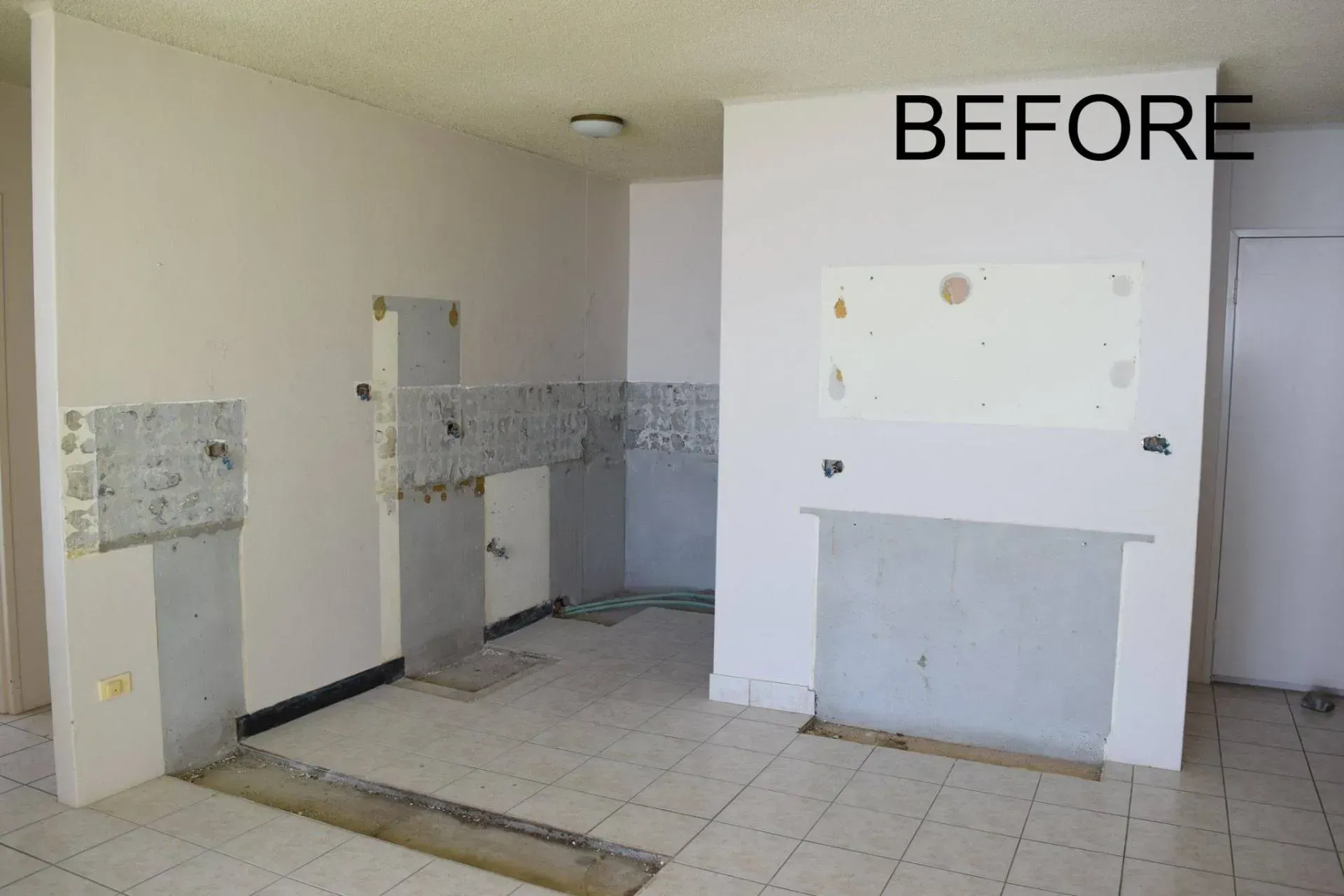 A before photo of a kitchen renovation with partially removed walls and tile.