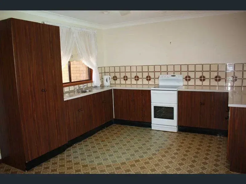A retro kitchen with dark wood cabinets, patterned tile floor, and a white stove.