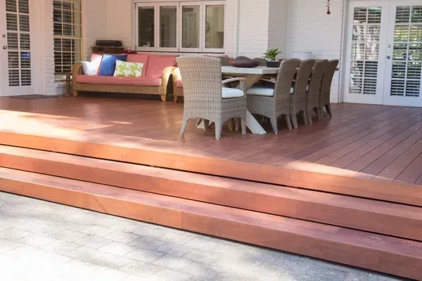 Wooden deck with steps leading to outdoor seating area and a dining table.