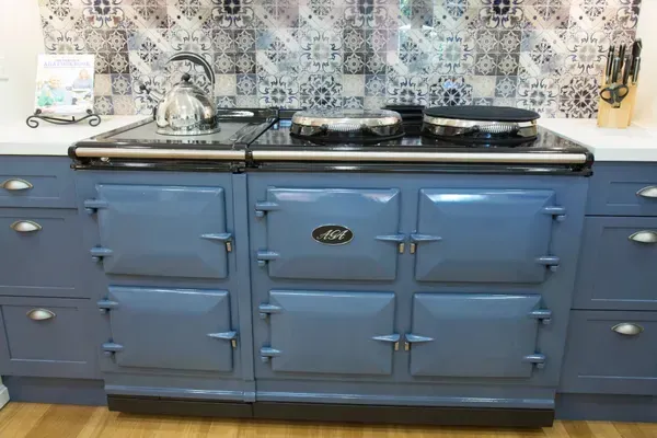 Blue oven and stovetop against blue and white tiled backsplash in kitchen.