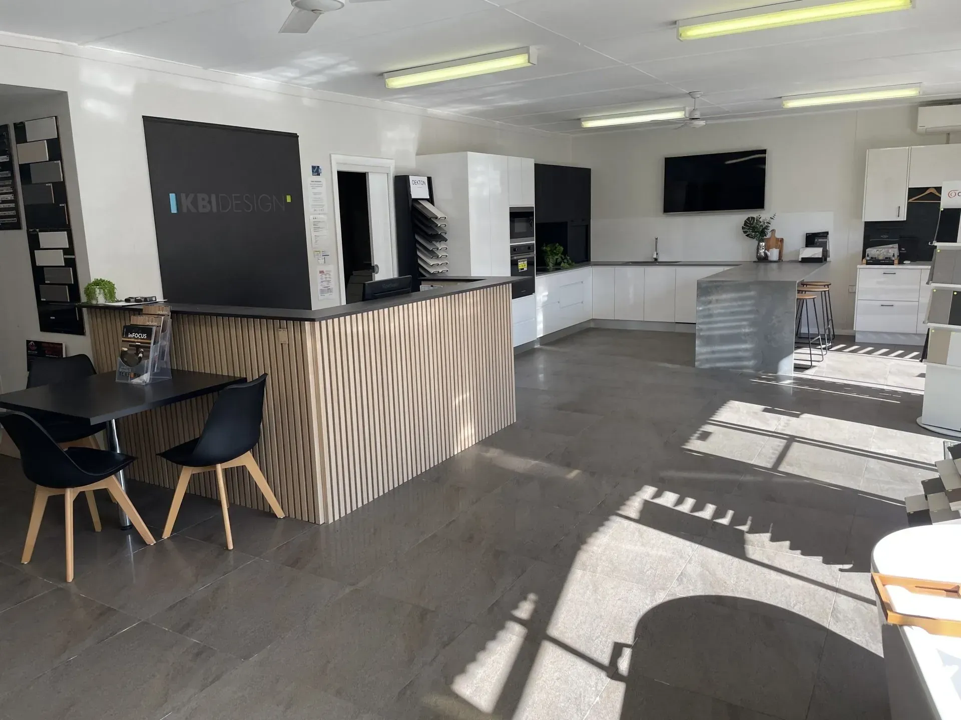 Interior showroom with kitchen displays, tables, and chairs under bright lights.