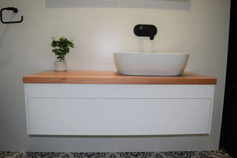 White floating bathroom vanity with a wood countertop and a white sink.