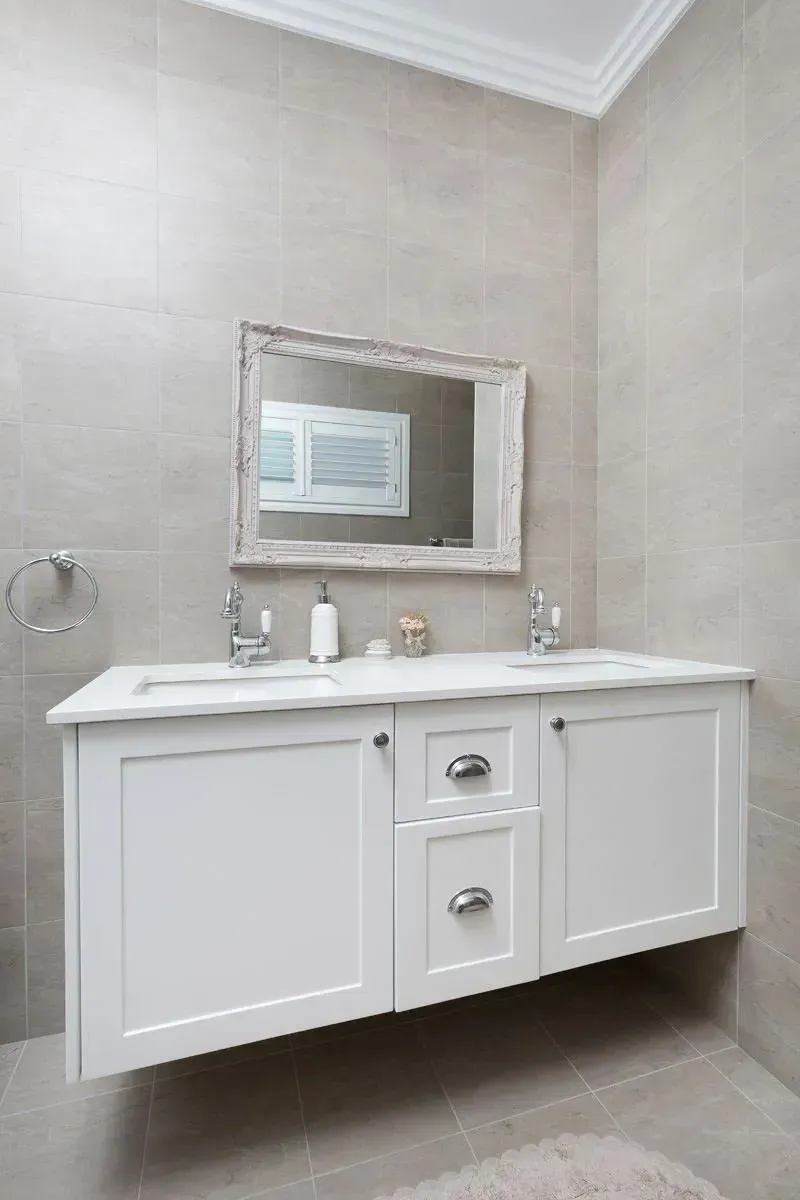 White floating bathroom vanity with double sinks and framed mirror.
