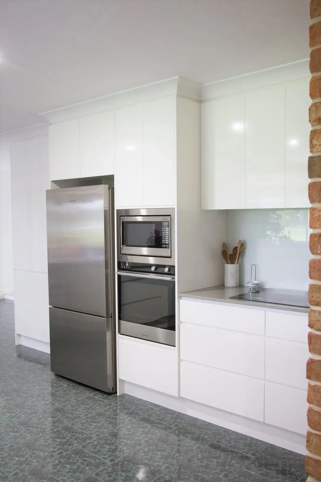 Modern kitchen with stainless steel refrigerator, white cabinets, and built-in microwave and oven.