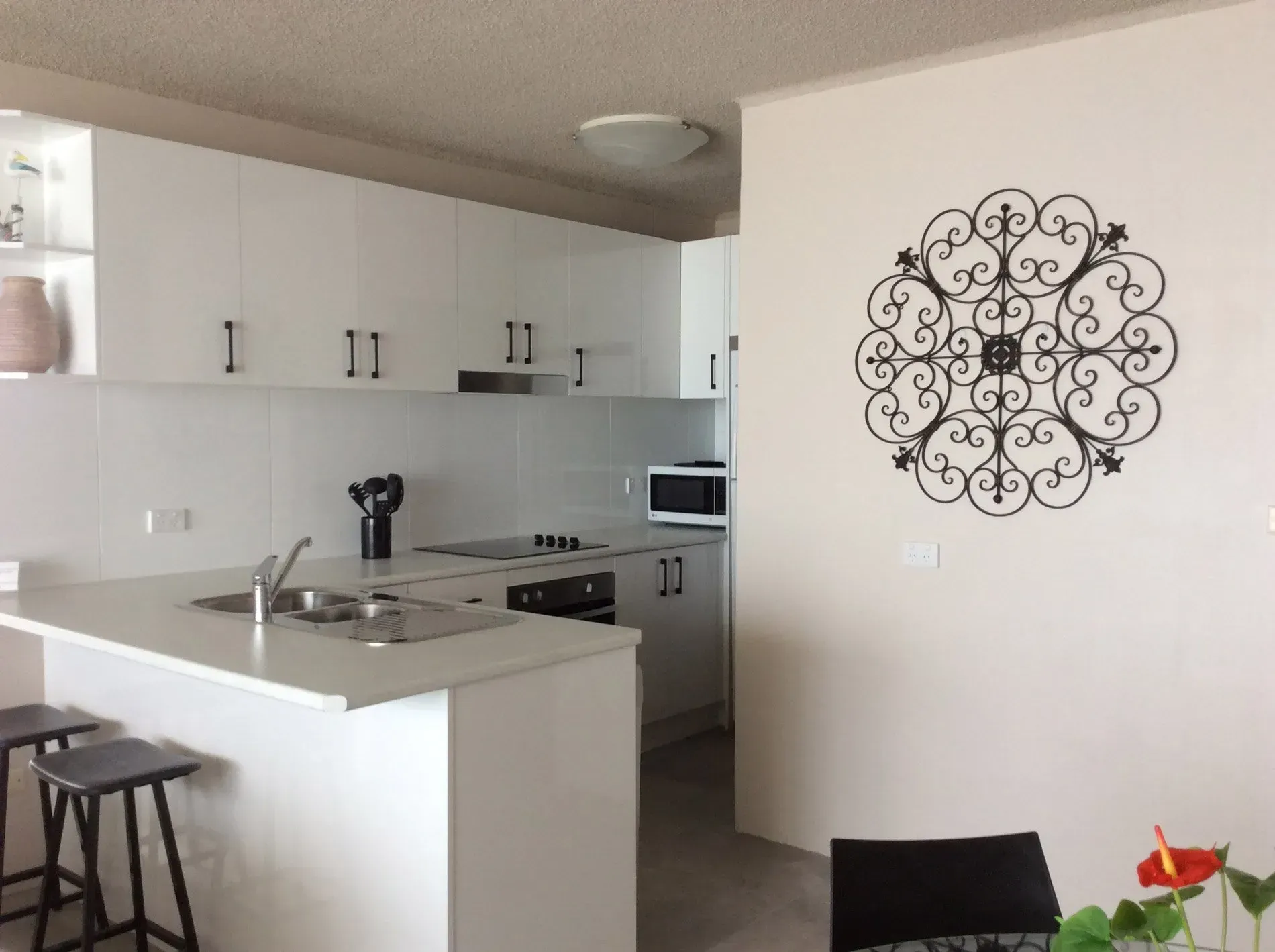 White modern kitchen with a decorative wall piece.