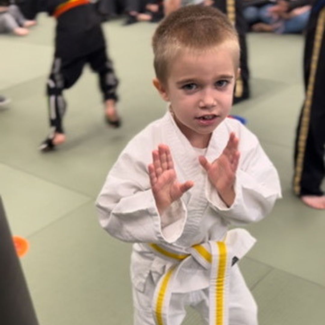A group of young girls are practicing karate in a gym.